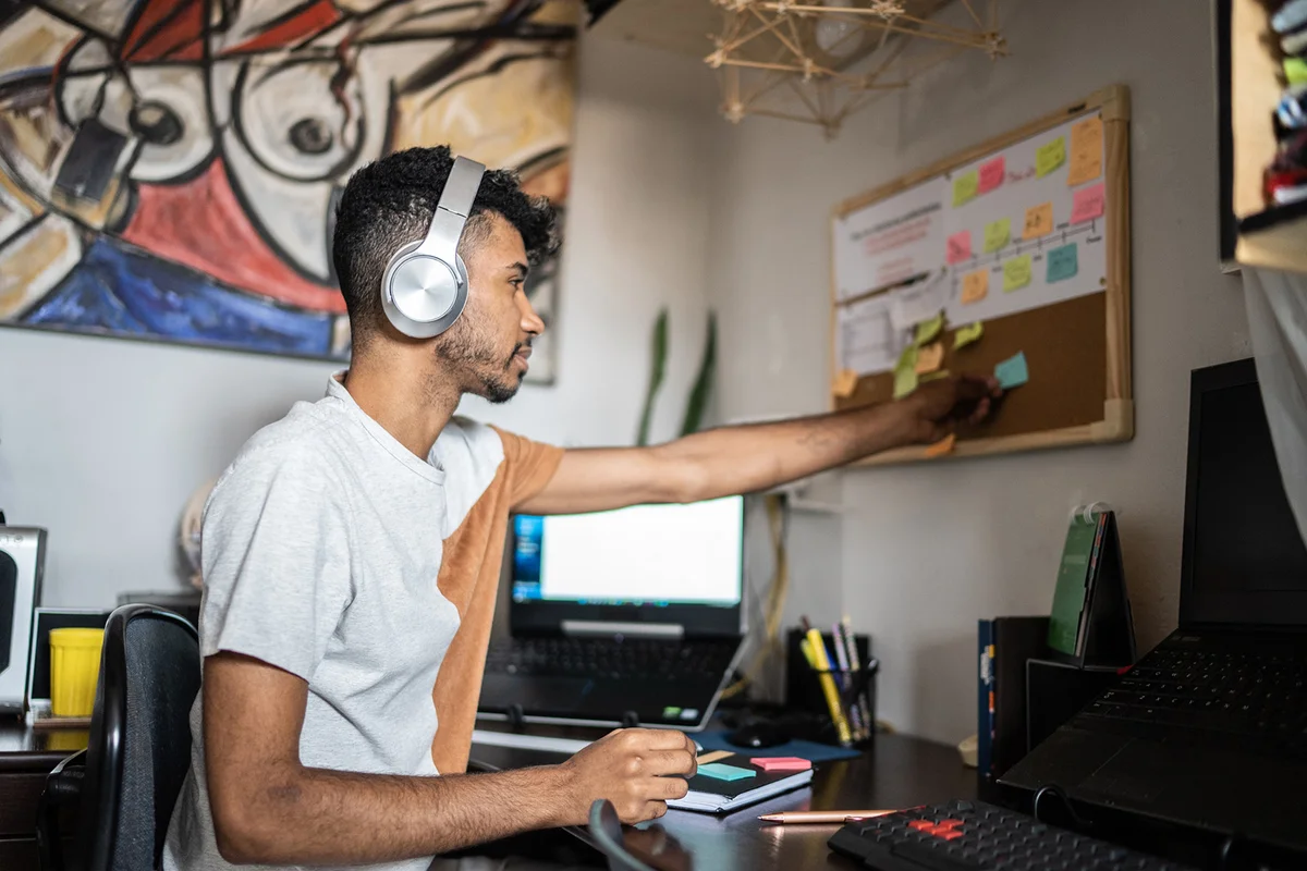 Young man organizing ideas and posting them at home