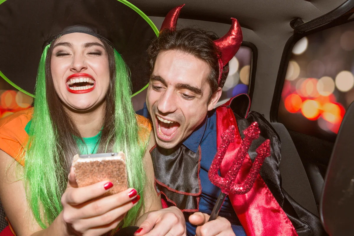 Halloween witch and devil laughing in back of car