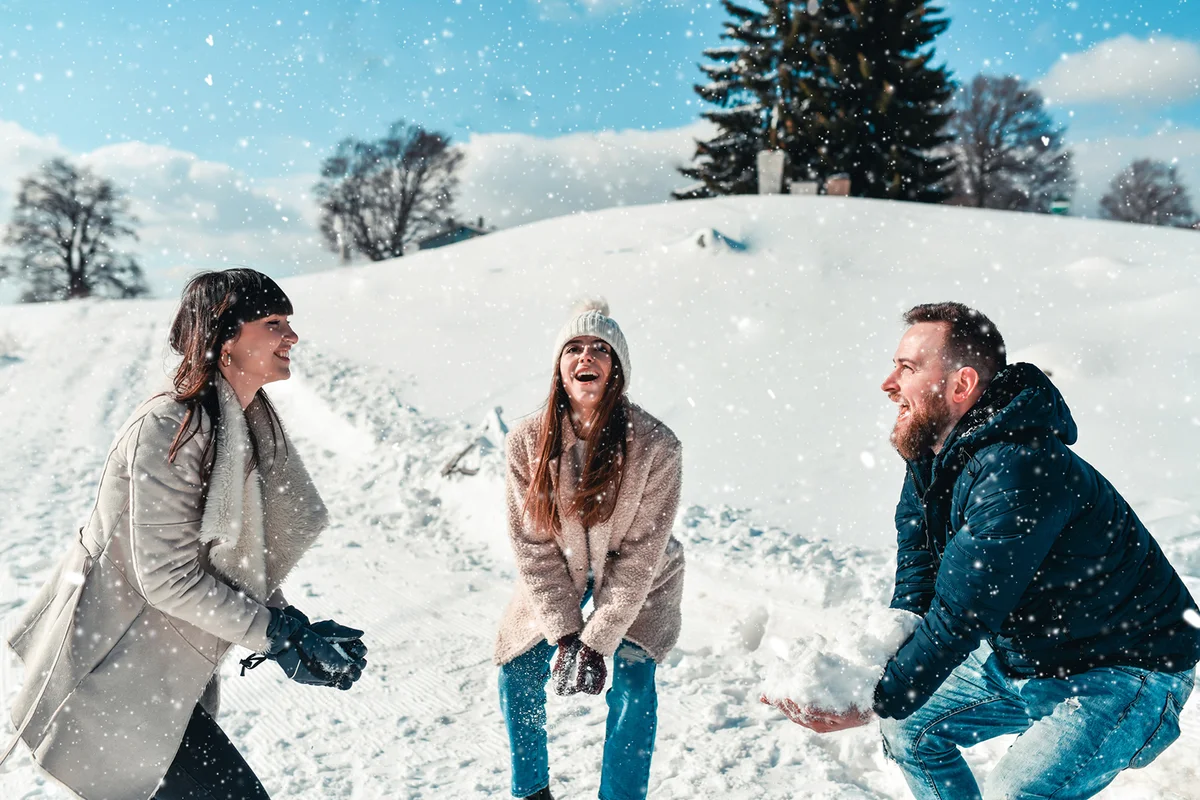 Happy Friends Throwing Snow In Air On Mountain