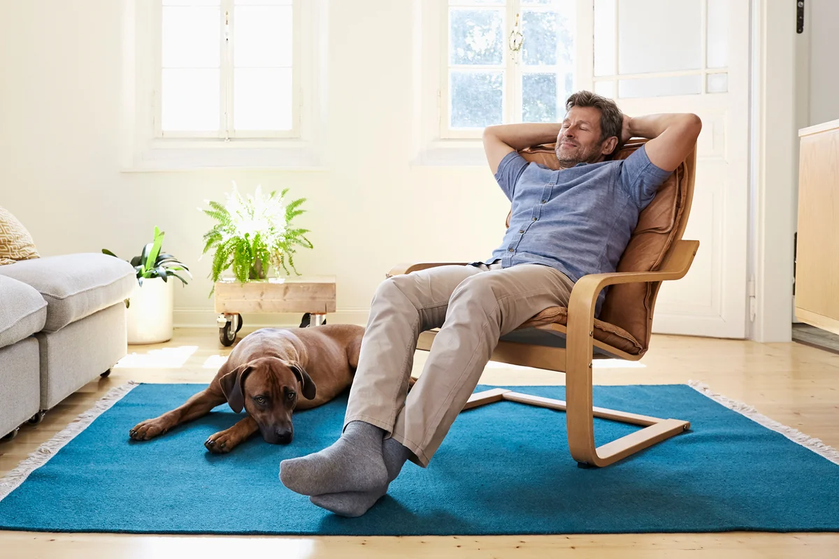 Man relaxing at home with his dog by his side