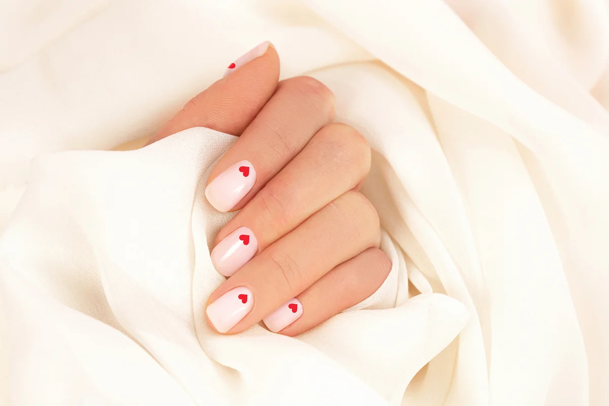 woman's hand with pastel color manicure and red hearts