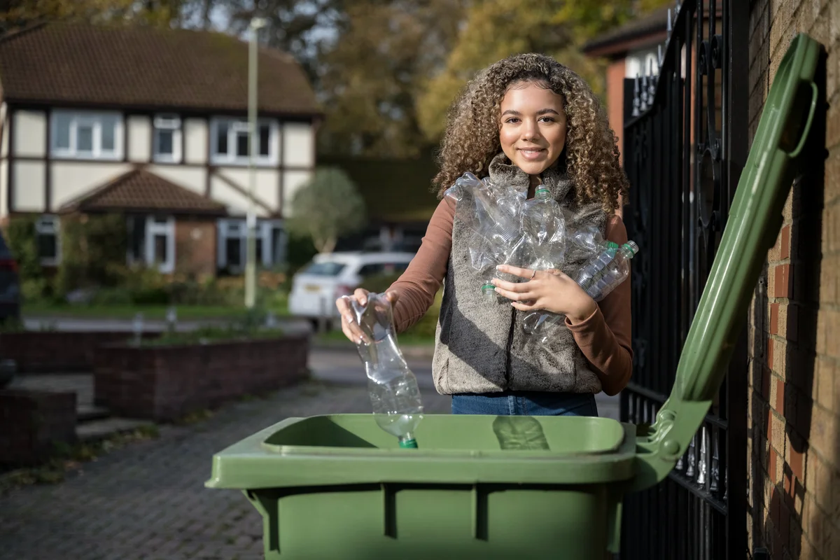 woman putting recyclables in the garbage can