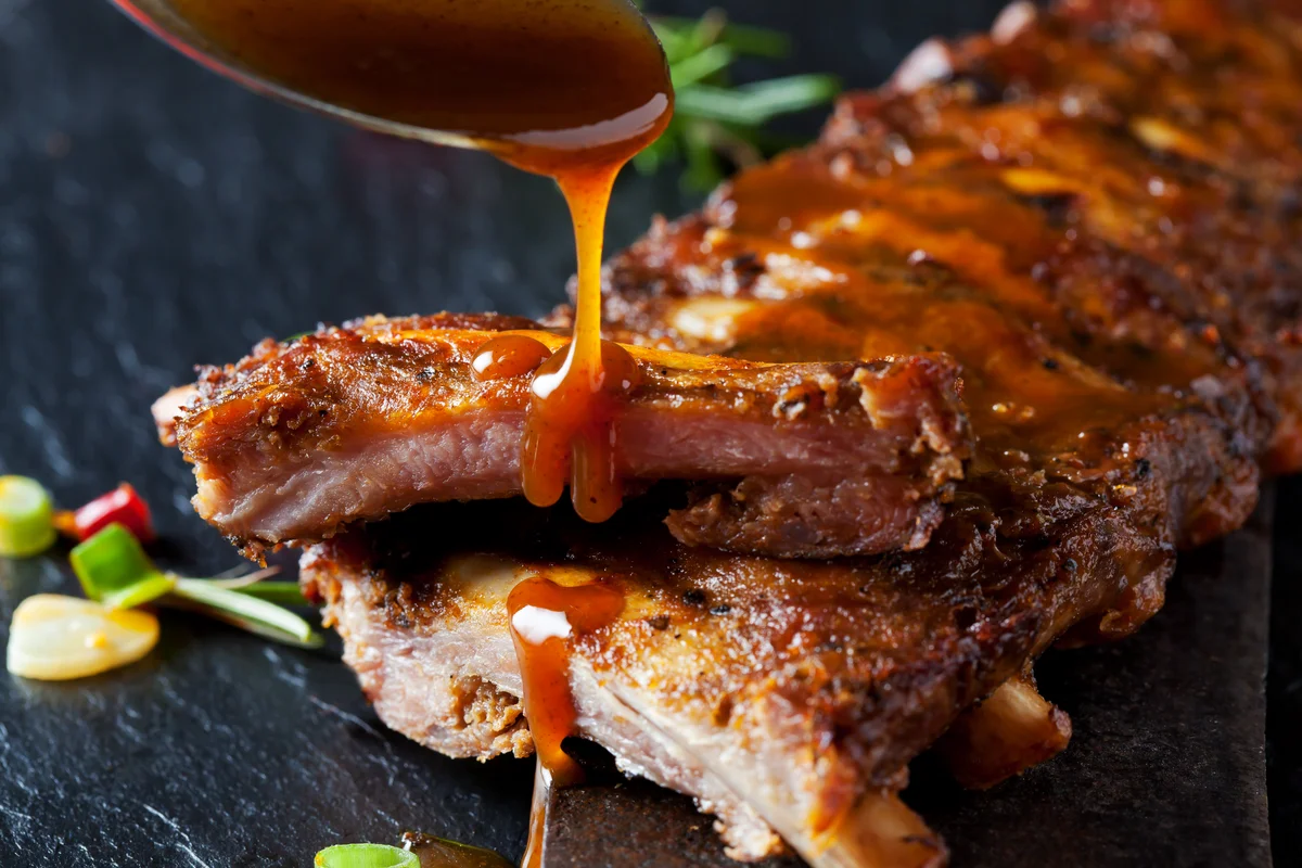 drizzling sauce over cooked ribs