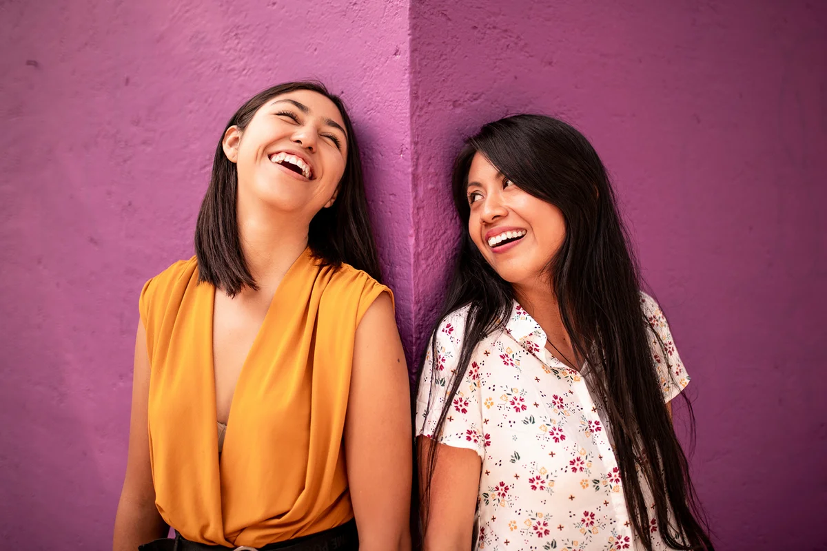 Two beautiful women laughing at the street corner