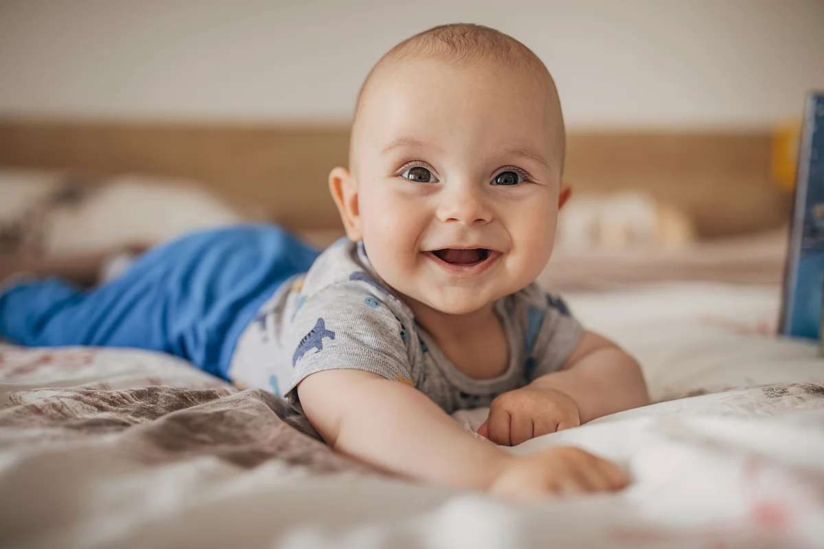 Beautiful baby boy lying on bed and smiling