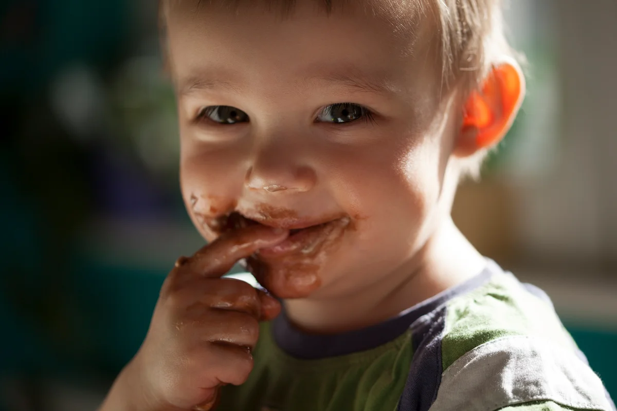 Smiling little boy eating chocolate