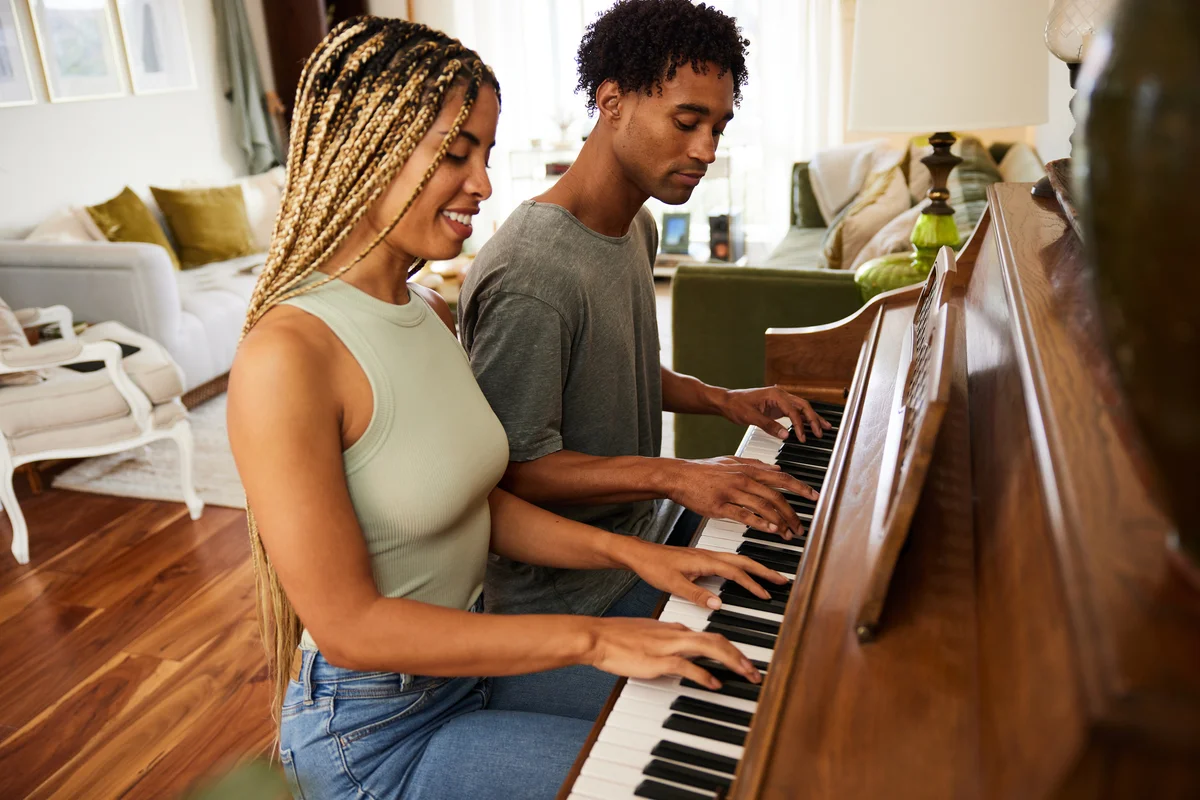 Young couple playing the piano in their living room