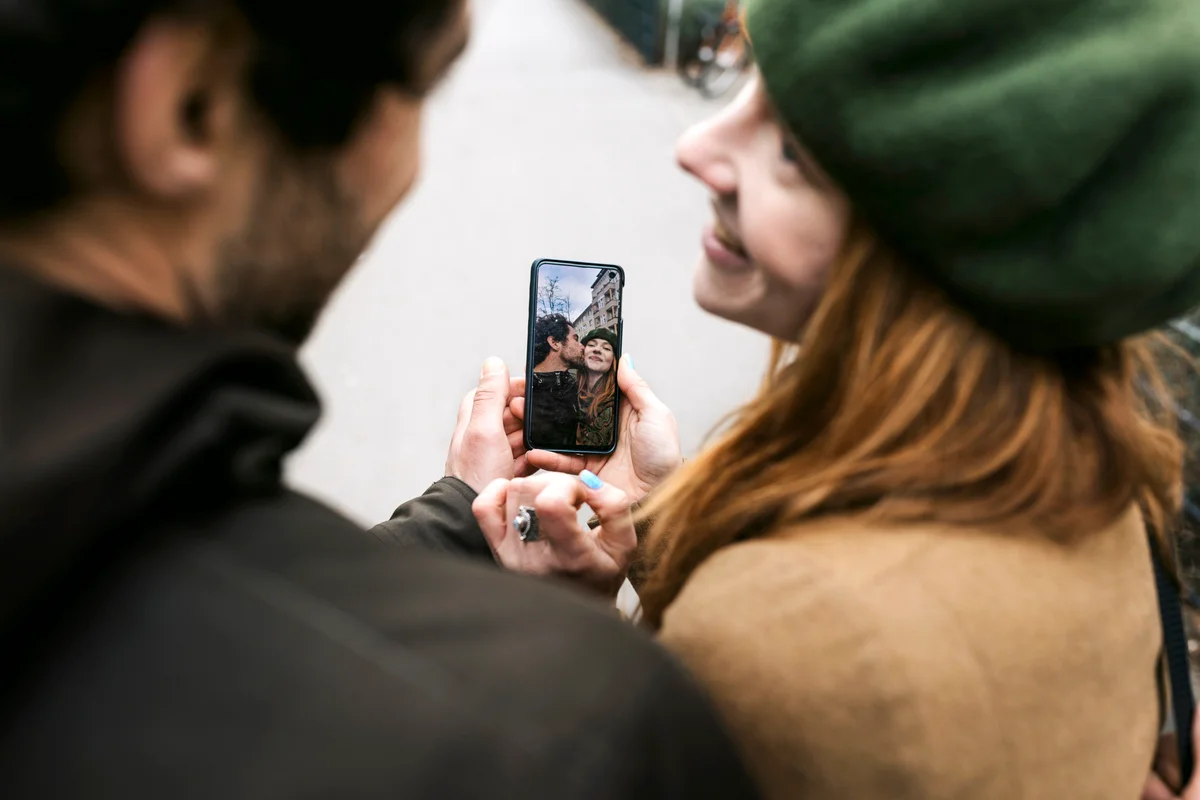 Couple smiling while looking at selfies on smartphone