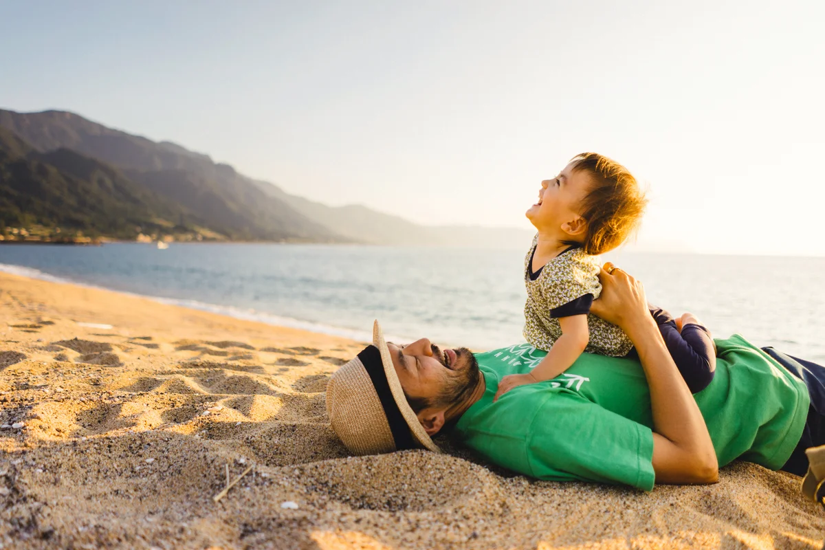 Father and child on beach at sunset