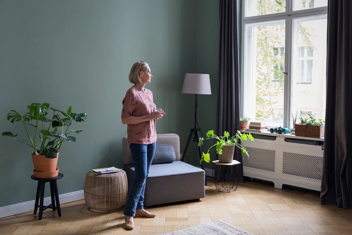 Woman standing in room with plants on various stands