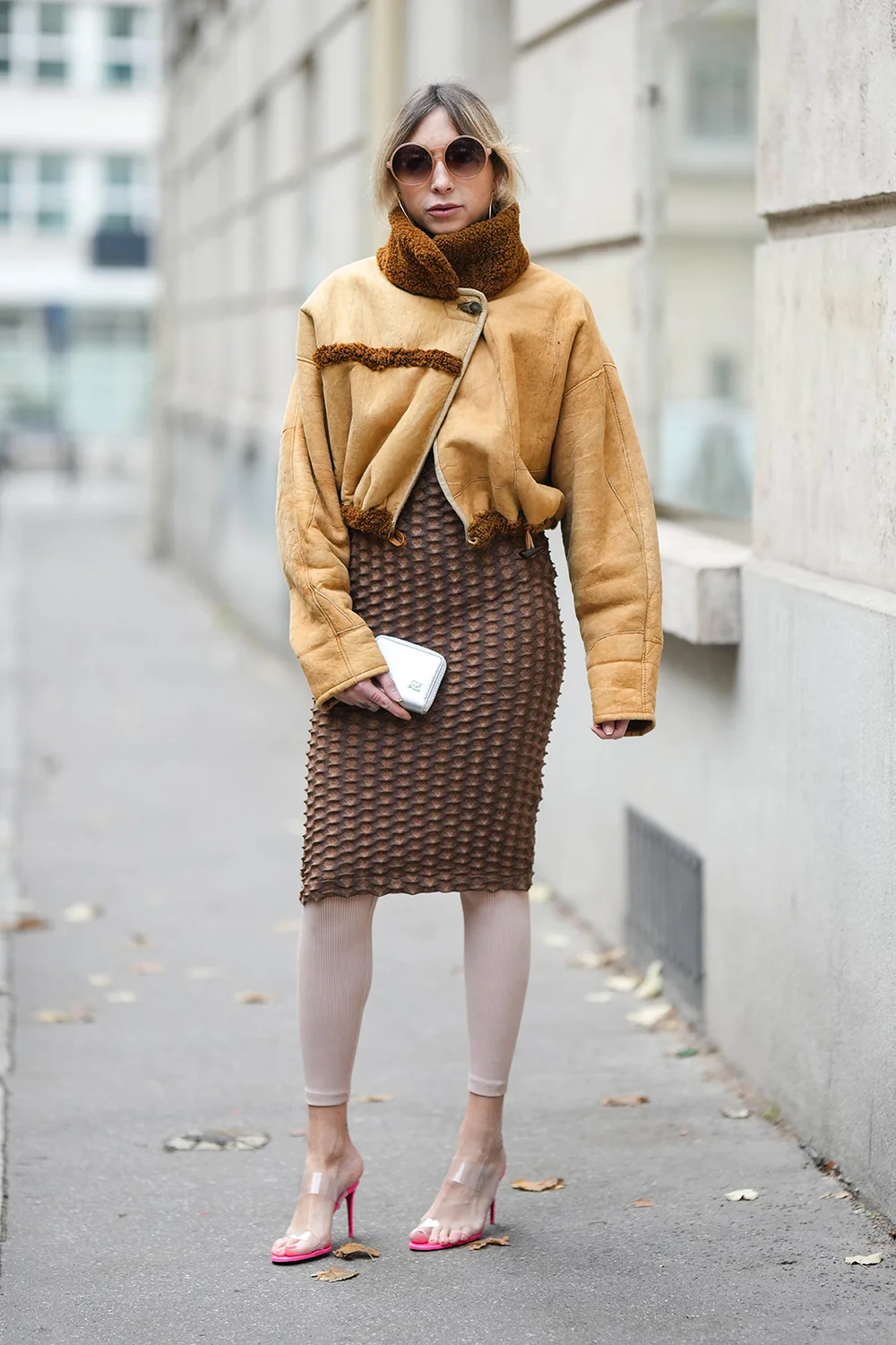 Emy Venturini wears yellow suede and brown sheep borders cropped / zipper aviator jacket, a brown embossed polka dots pattern knees dress and white leggings