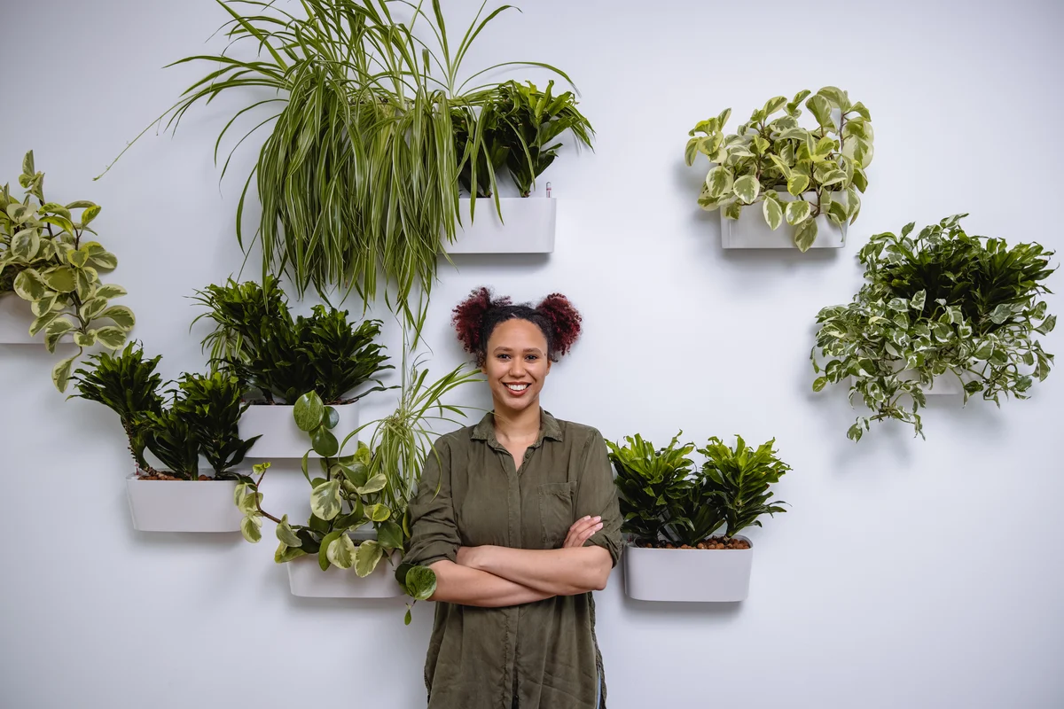 Woman standing in front of wall that has mounted plants.