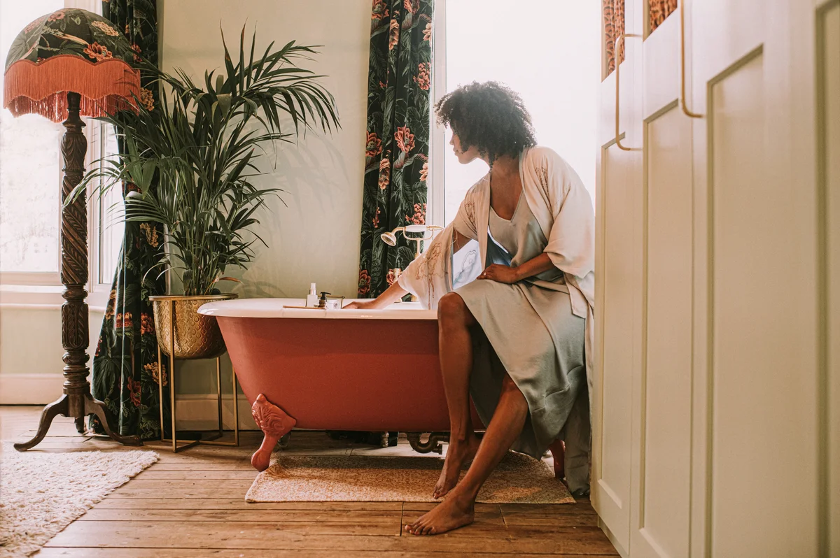 Woman sitting on bathtub with beautiful palm
