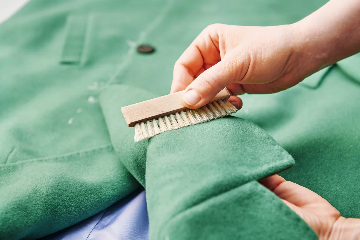 Woman cleaning coat fabric with a small brush