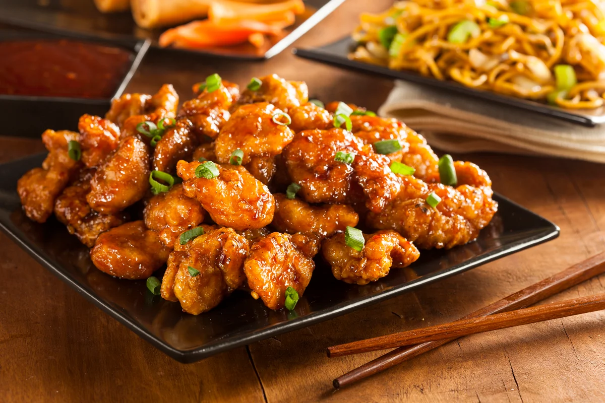 Image of a plate filled with orange chicken topped with green onions.