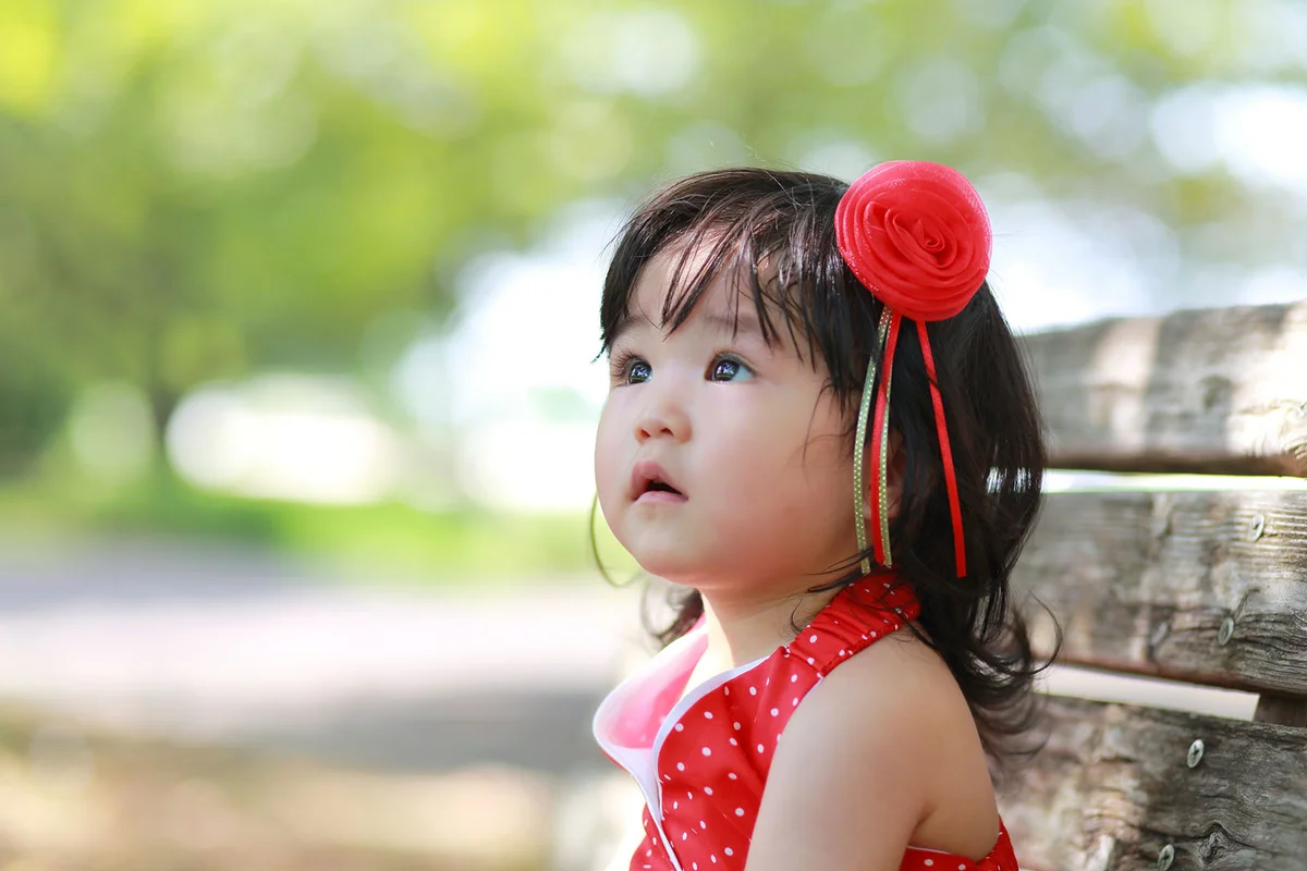 baby wearing a red dress with flower and ribbon hair accessories