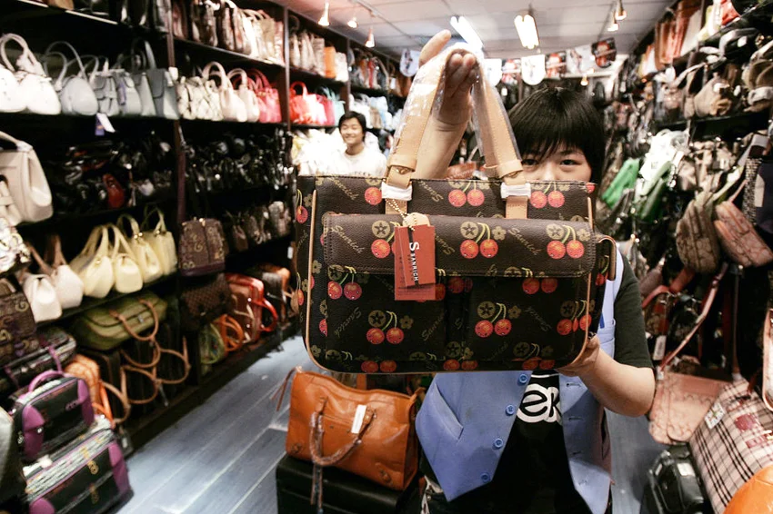 Vendor shows a bag based in one of Louis Vuitton's designs at a market in Beijing