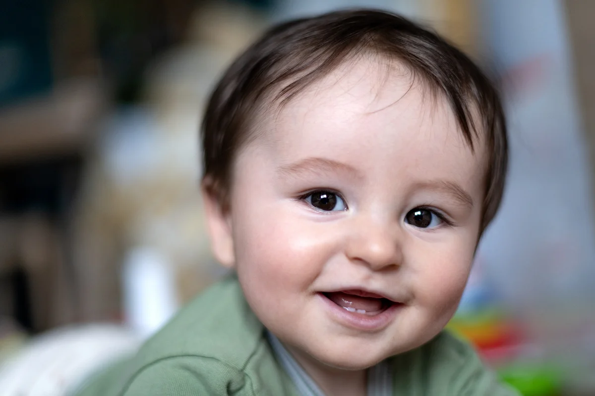 baby lying on floor looking at camera with his mouth open and smiling