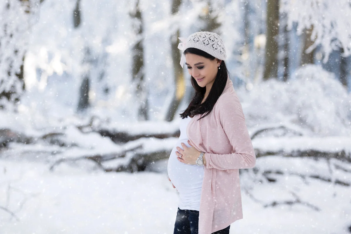 Smiling pregnant woman outdoors in snowfall
