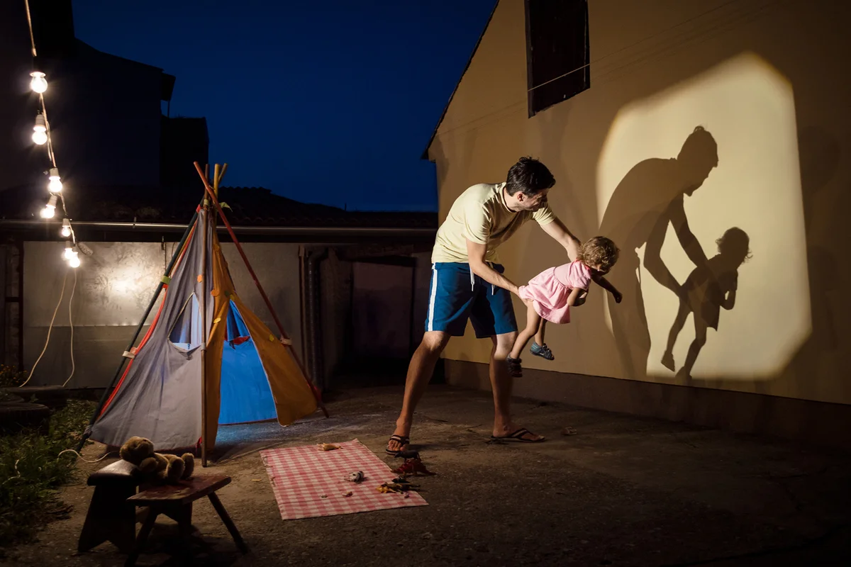 Fatherand daughter are playing with shadows in backyard of their home