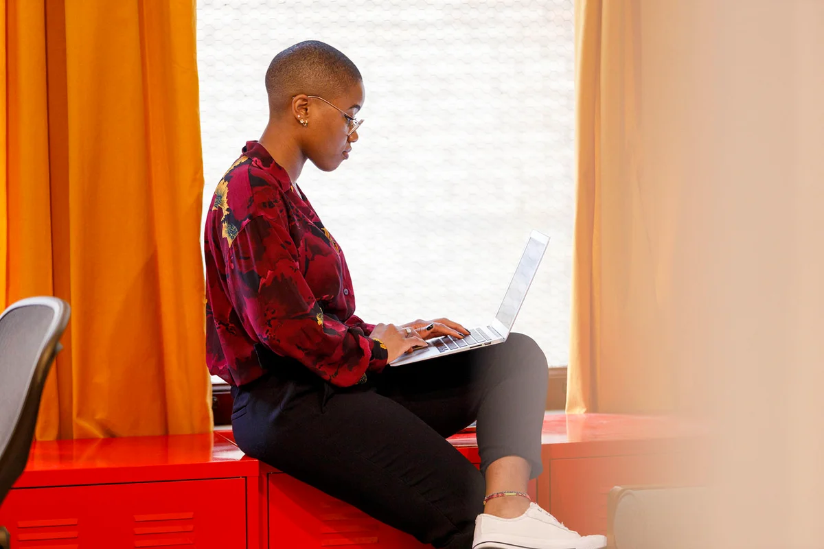 woman working on laptop near window in office -