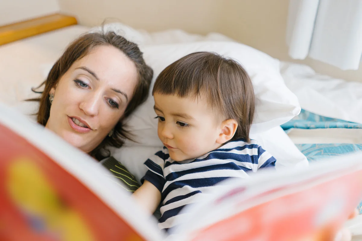 Mother reading a book to her child on a bed