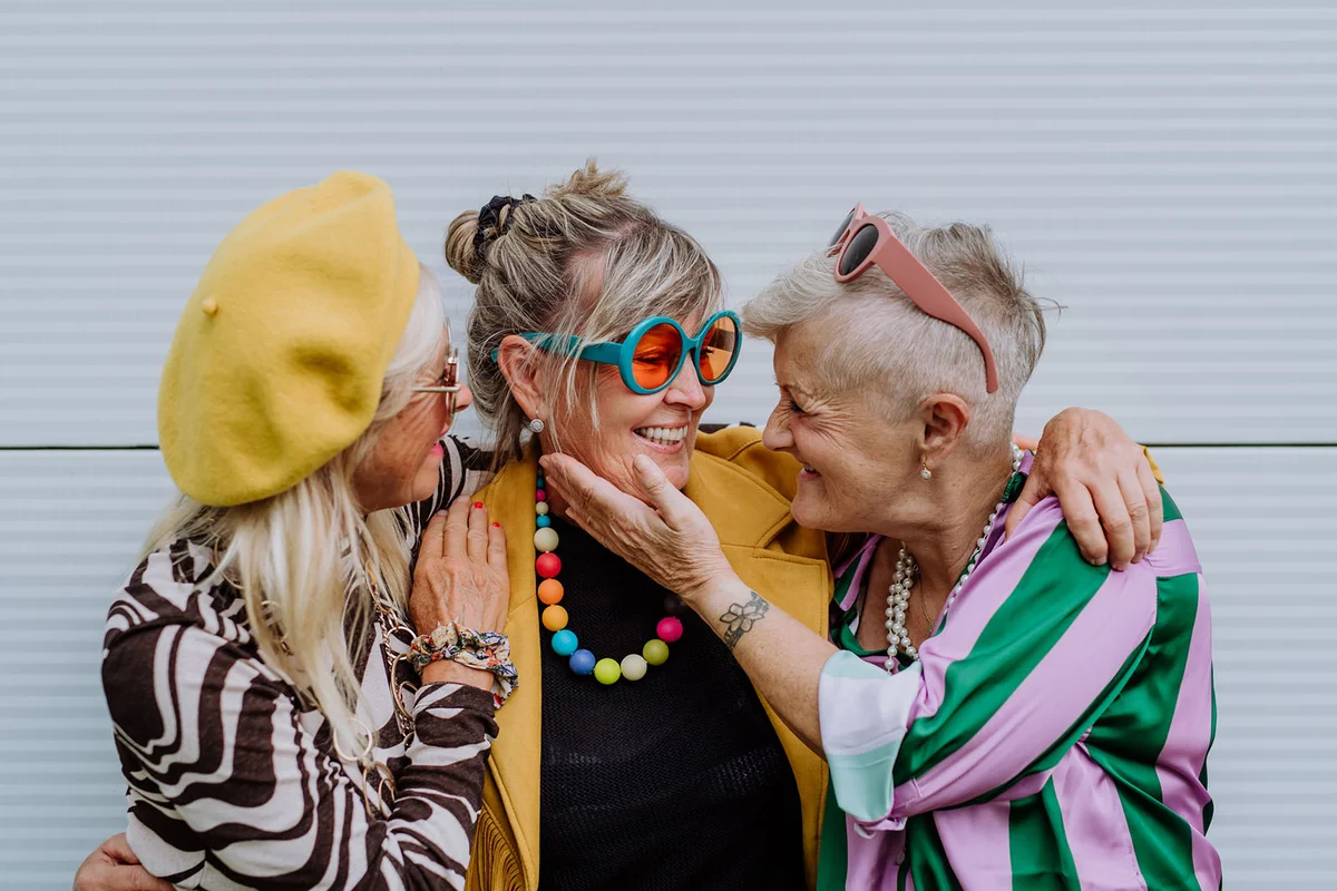 happy three senior friends in colourful clothes
