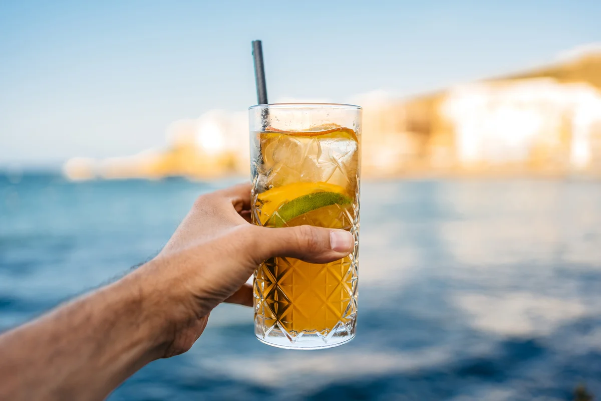Man Holding Ginger Lemonade Cocktail Against Blue Sea