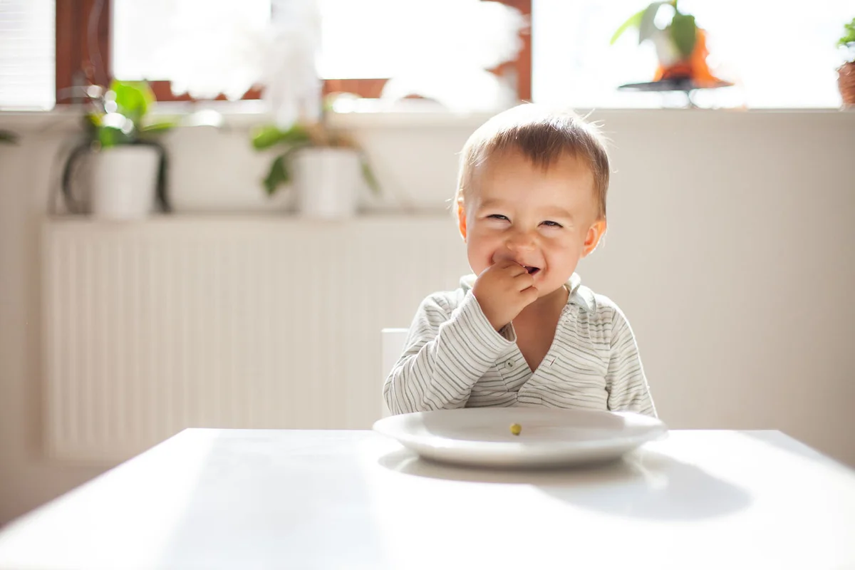 Baby boy eating peas