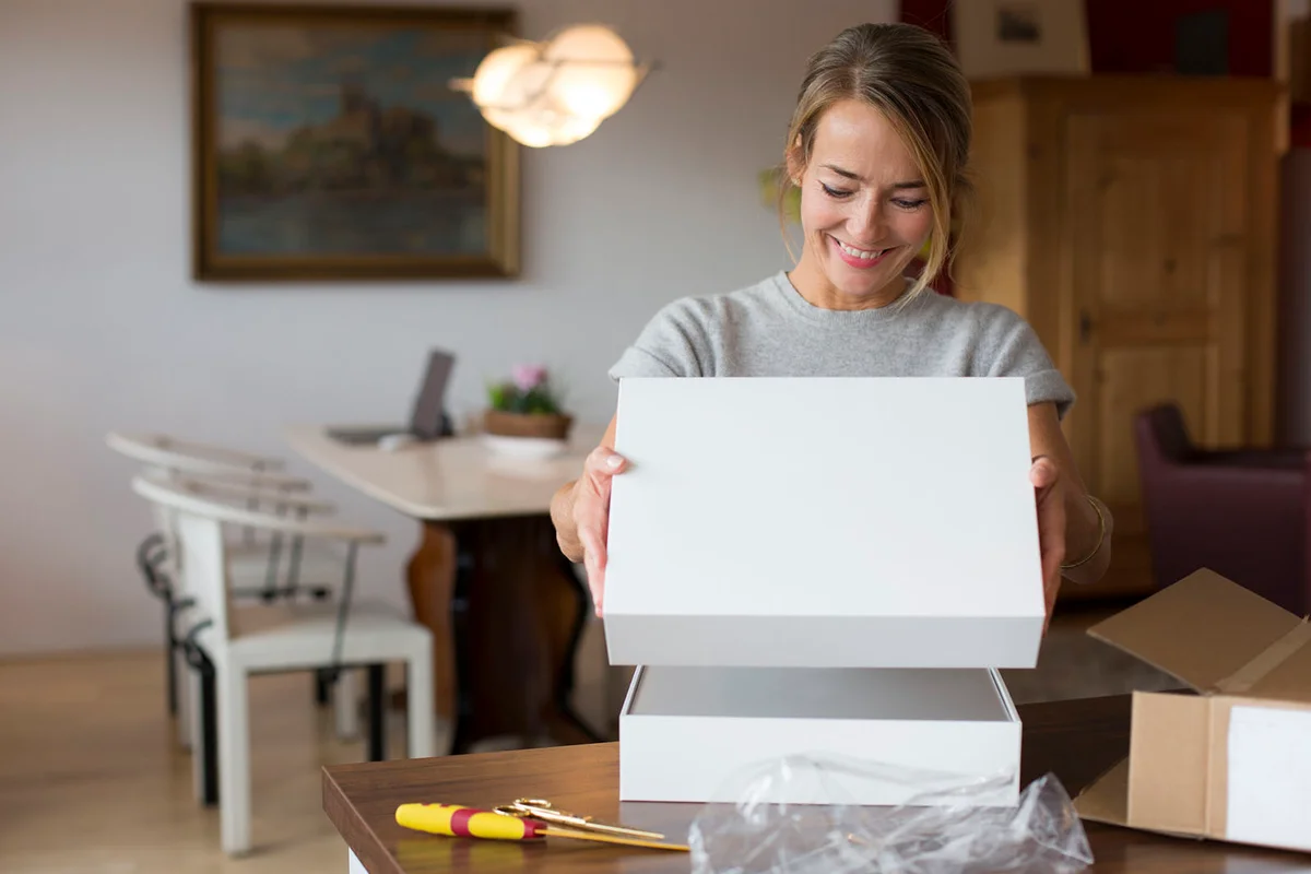 Happy woman opening parcel at home