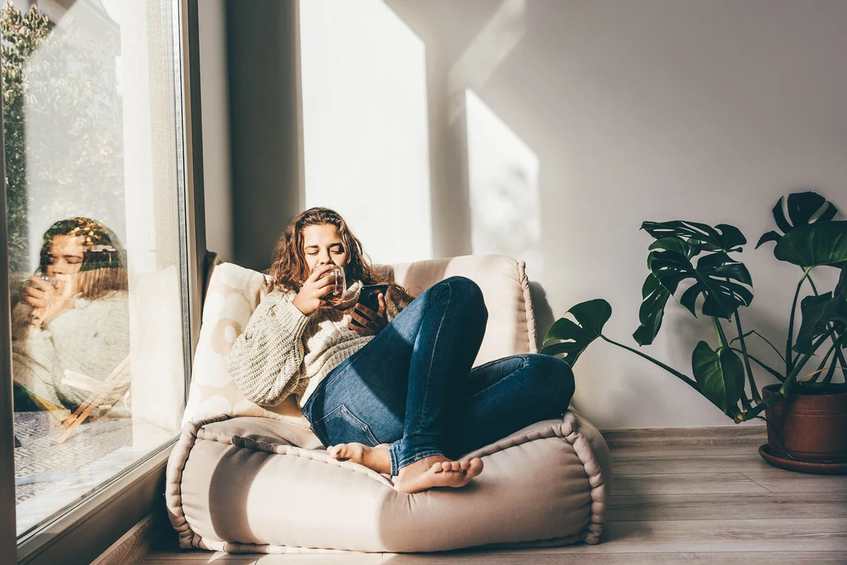 woman enjoying tea and using smartphone in the morning