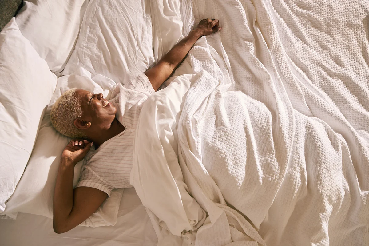 woman wakes up and stretches in early morning light