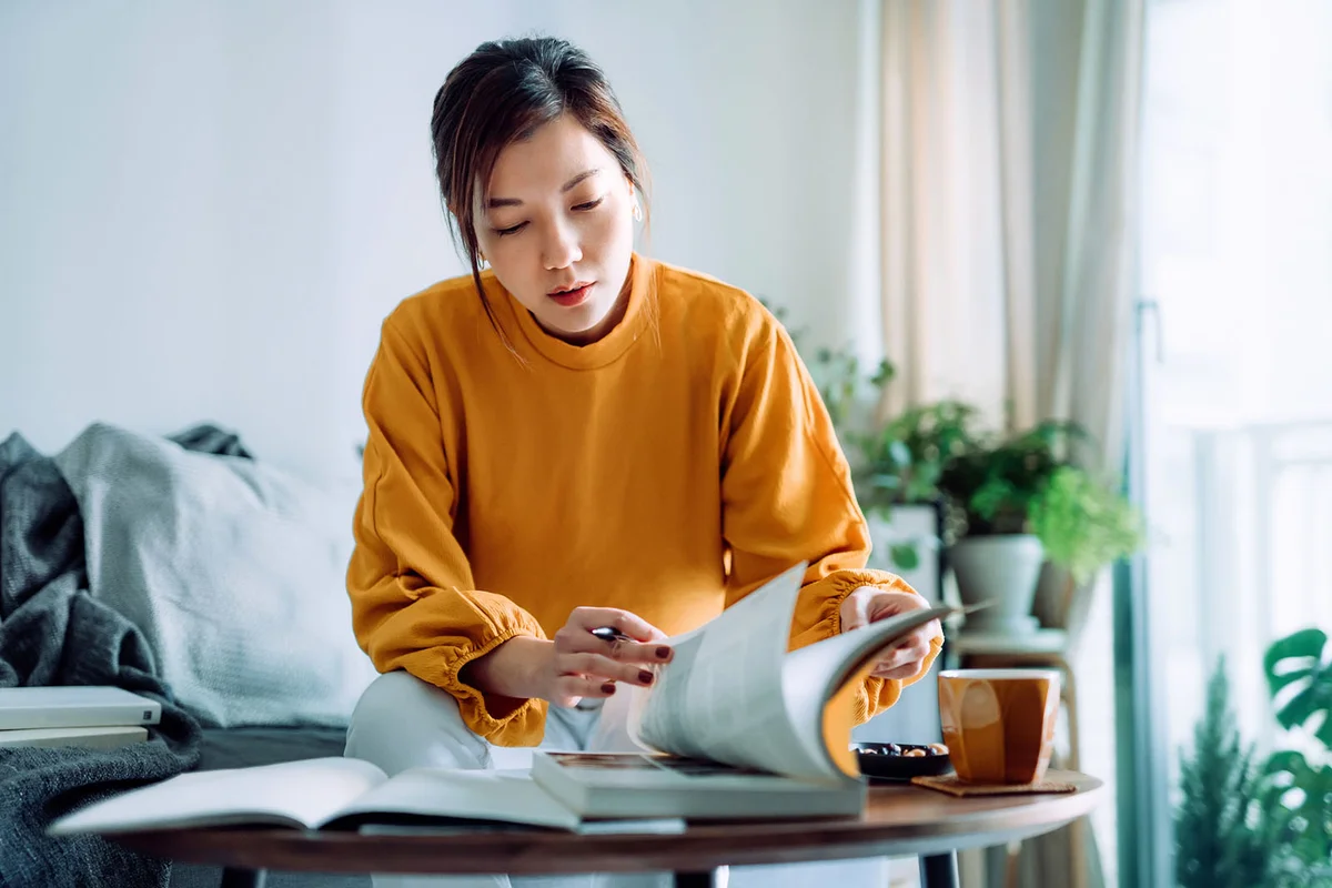 woman reading book and making notes at home