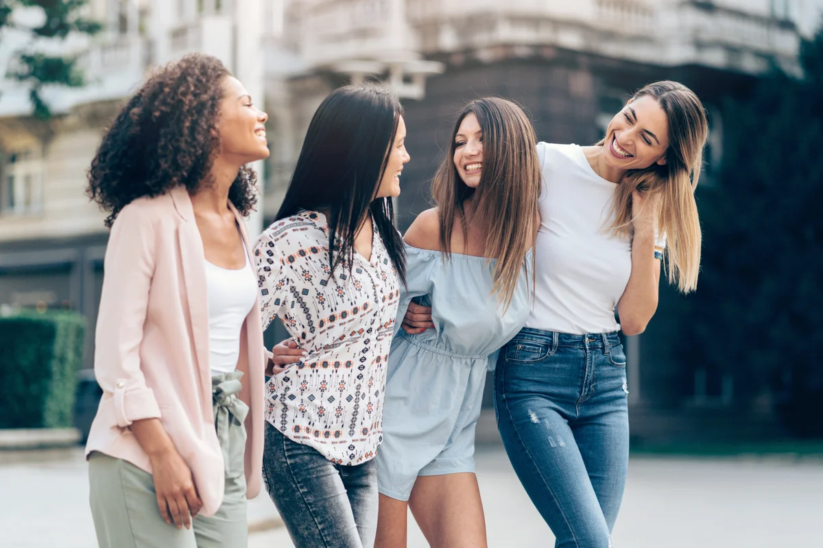Four happy girlfriends walking in the city
