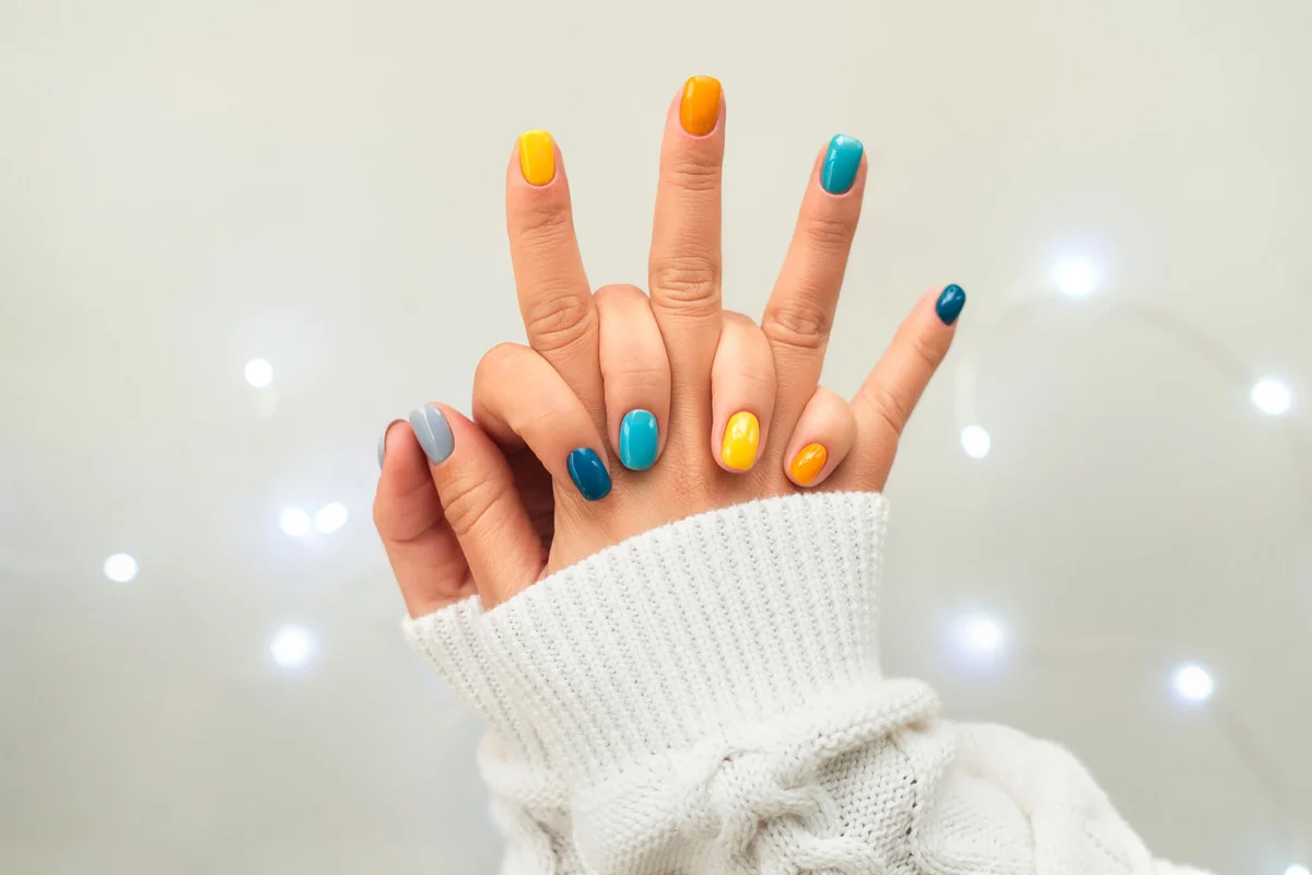 Trendy bright manicure on woman hands in white knitted sweater