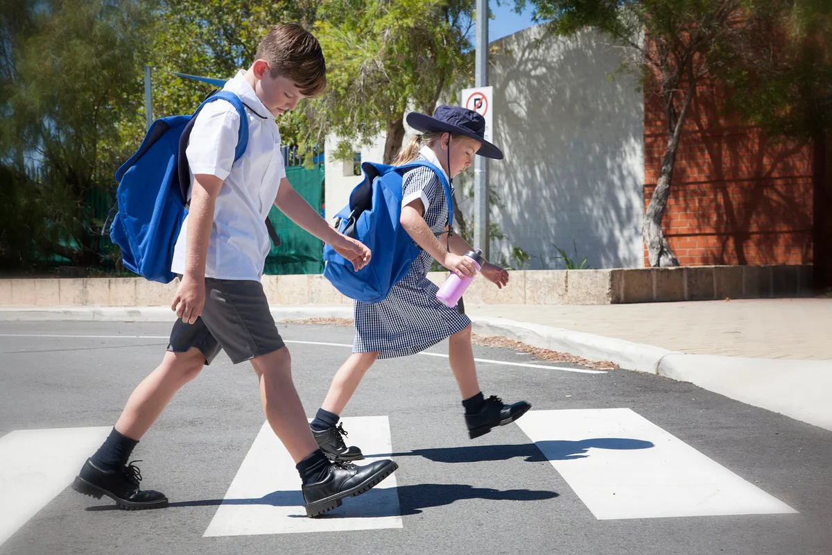 School children crossing the road safely at the cross walk