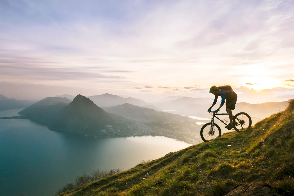 Mountain biker descends steep mountain slope above lake