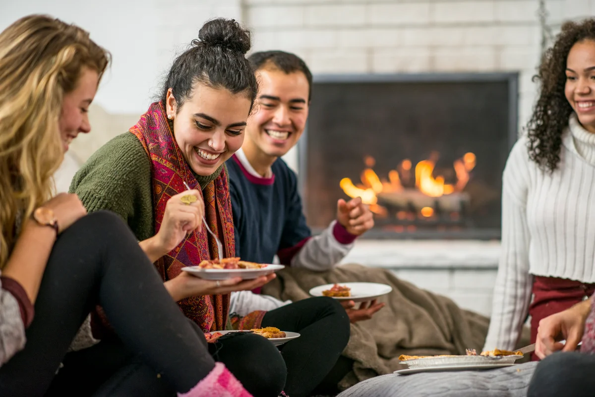 group of friends having dinner by a fire