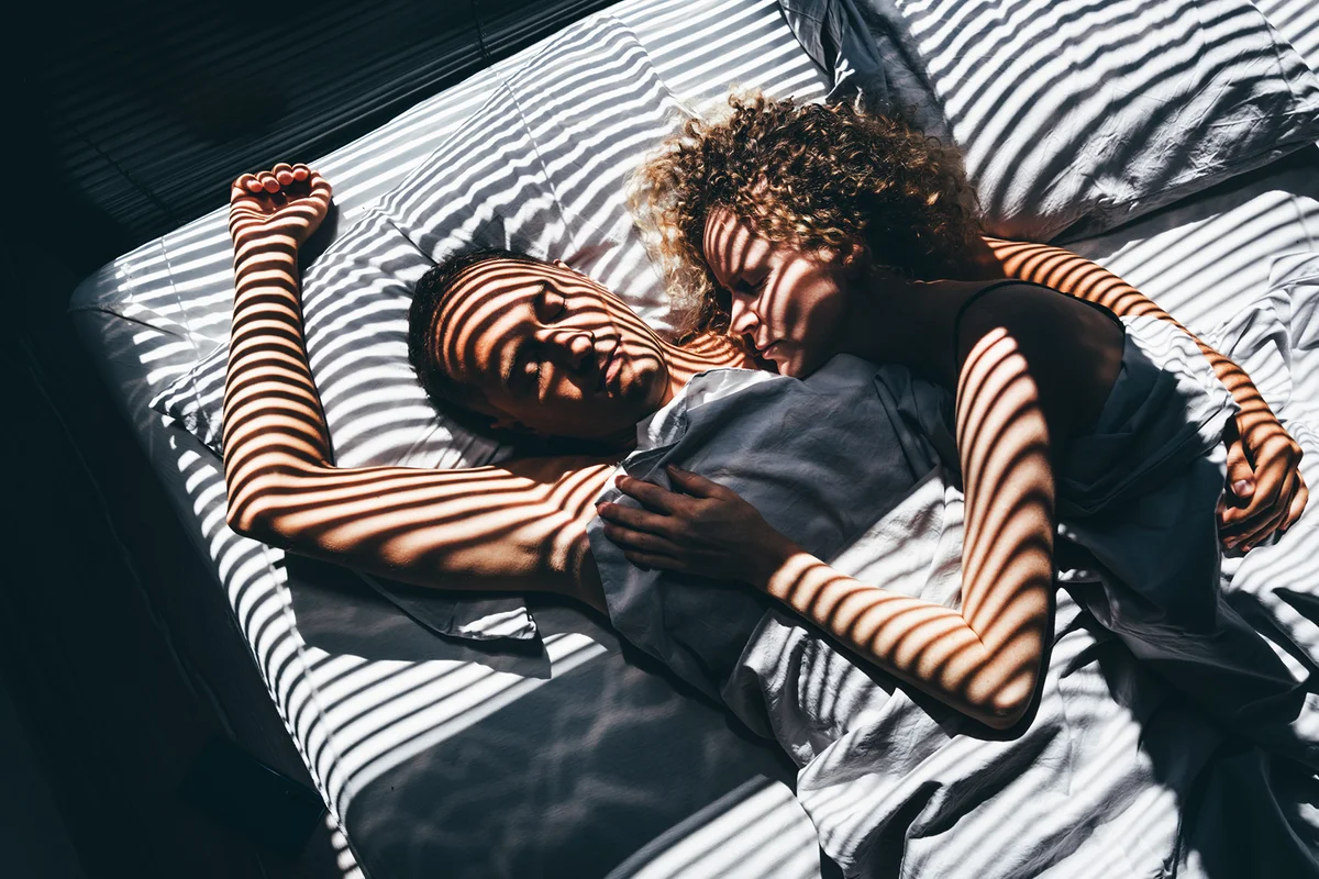 Couple asleep embracing in bed.