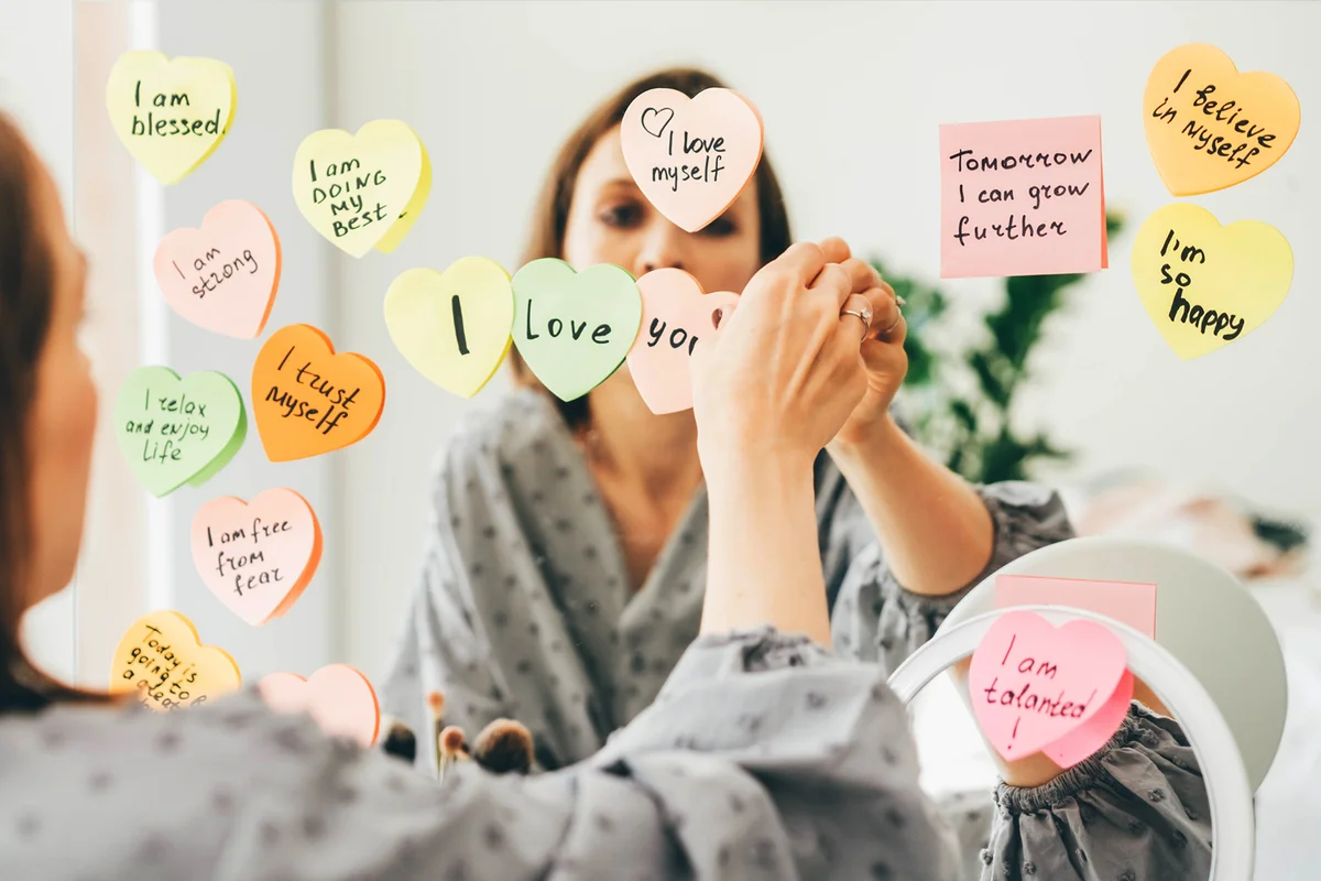 Woman stick a sticker with affirmations on the mirror