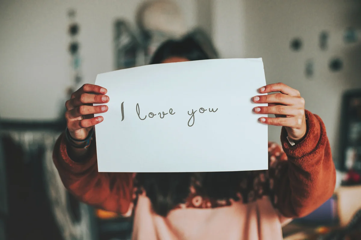Female holding a paper with I love you text