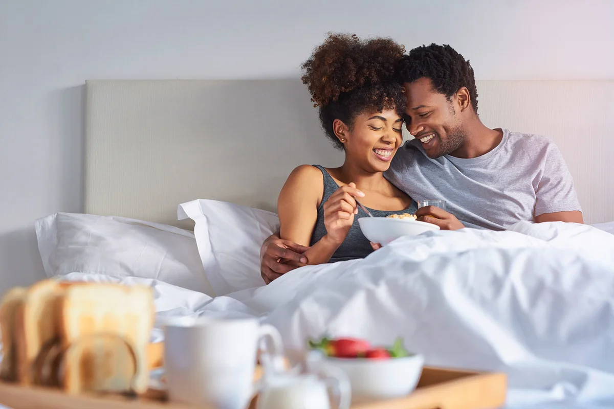 Shot of a happy young couple enjoying breakfast in bed
