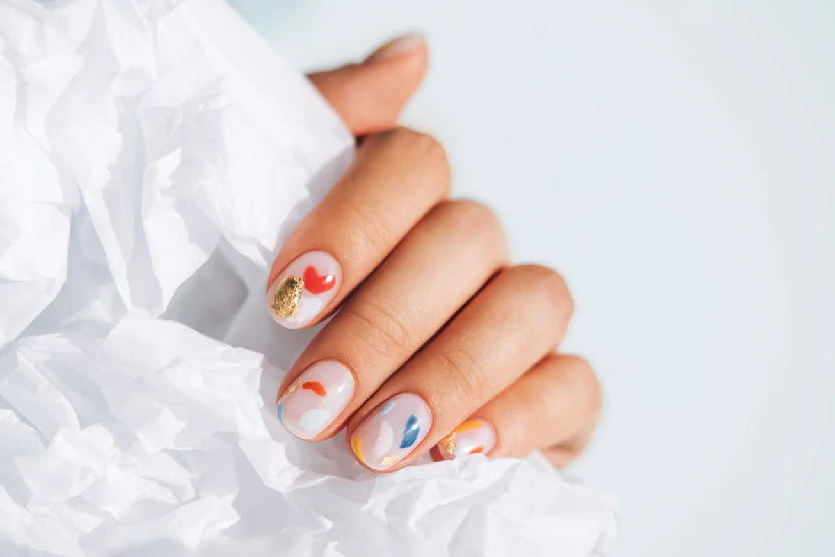 Woman hand with beautiful colorful manicure is holding white paper