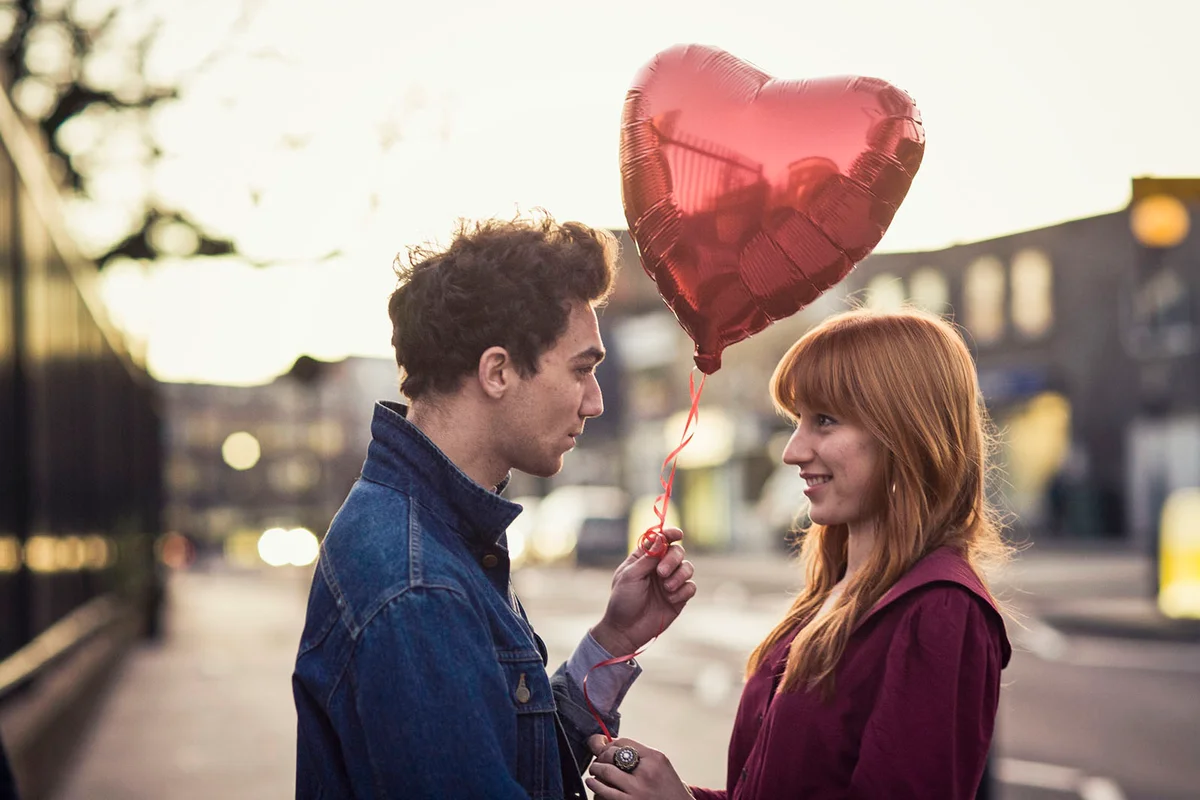 Couple walking with heart-shaped balloon
