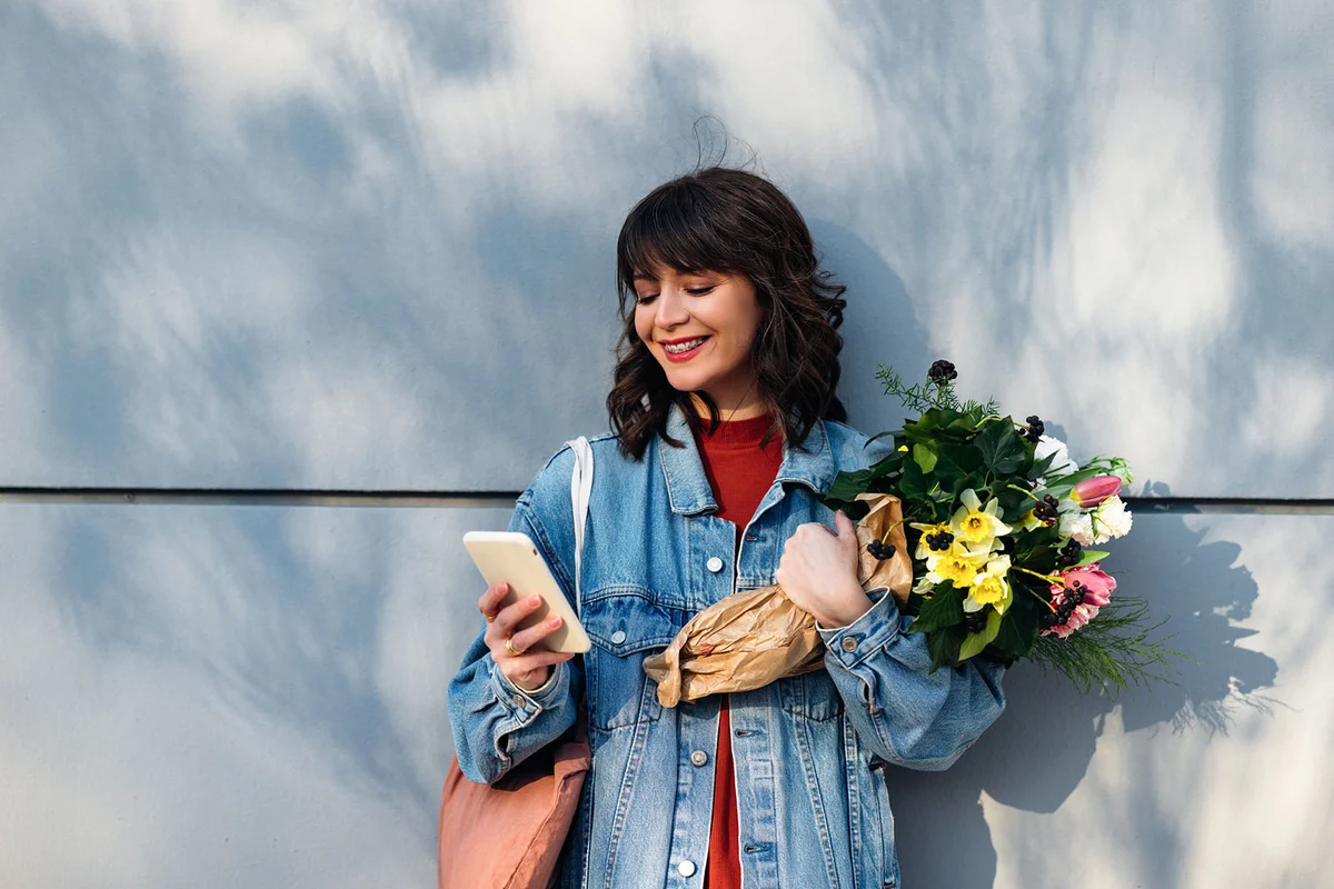 Beautiful Woman Leaning Against a Wall and Holding Flowers