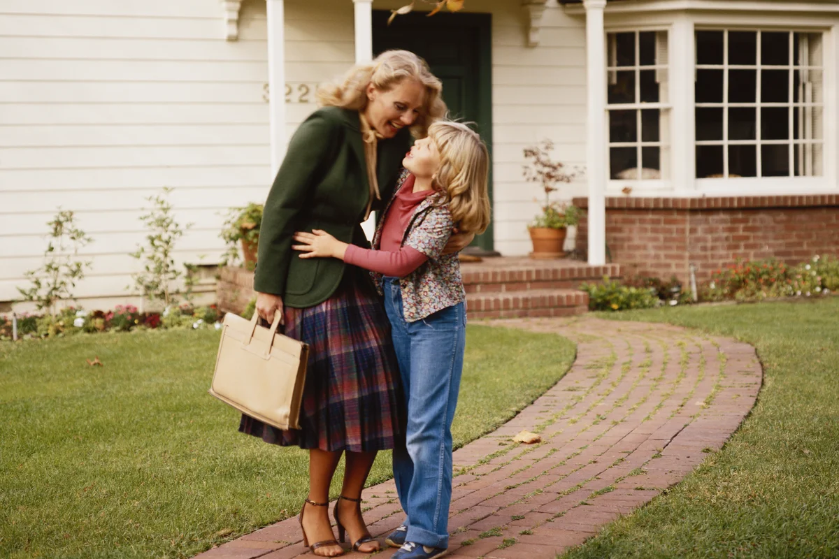 Mother embracing her daughter outside house