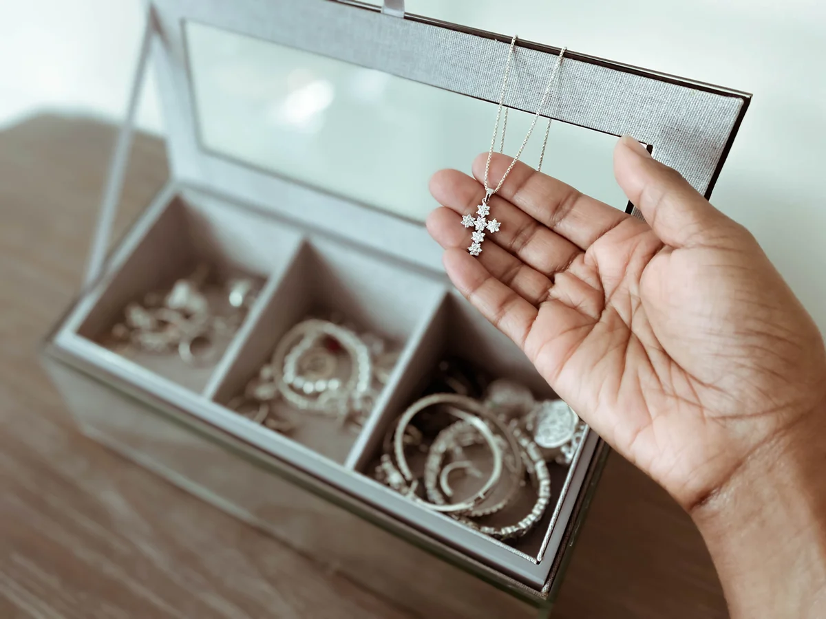 Woman Holds Necklace With Cross Pendant