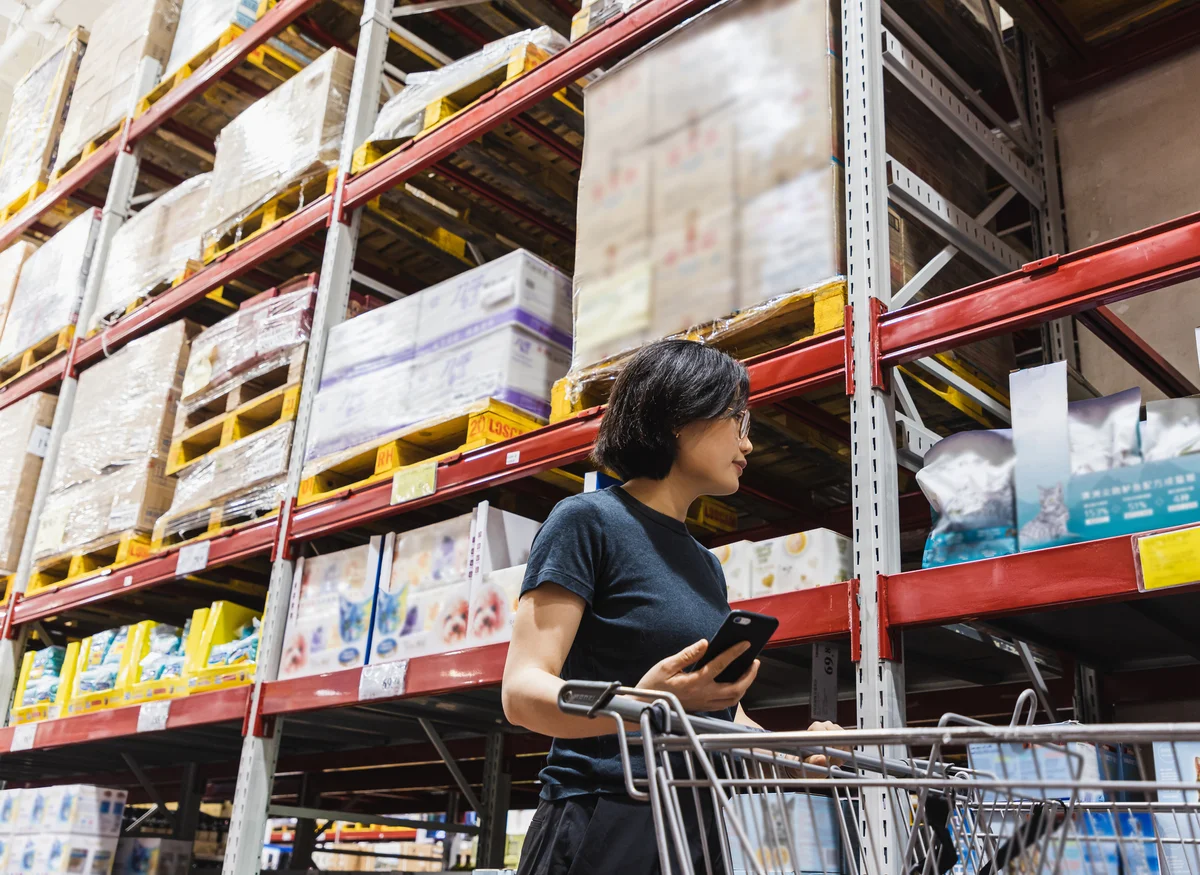 woman using phone while pushing a shopping cart