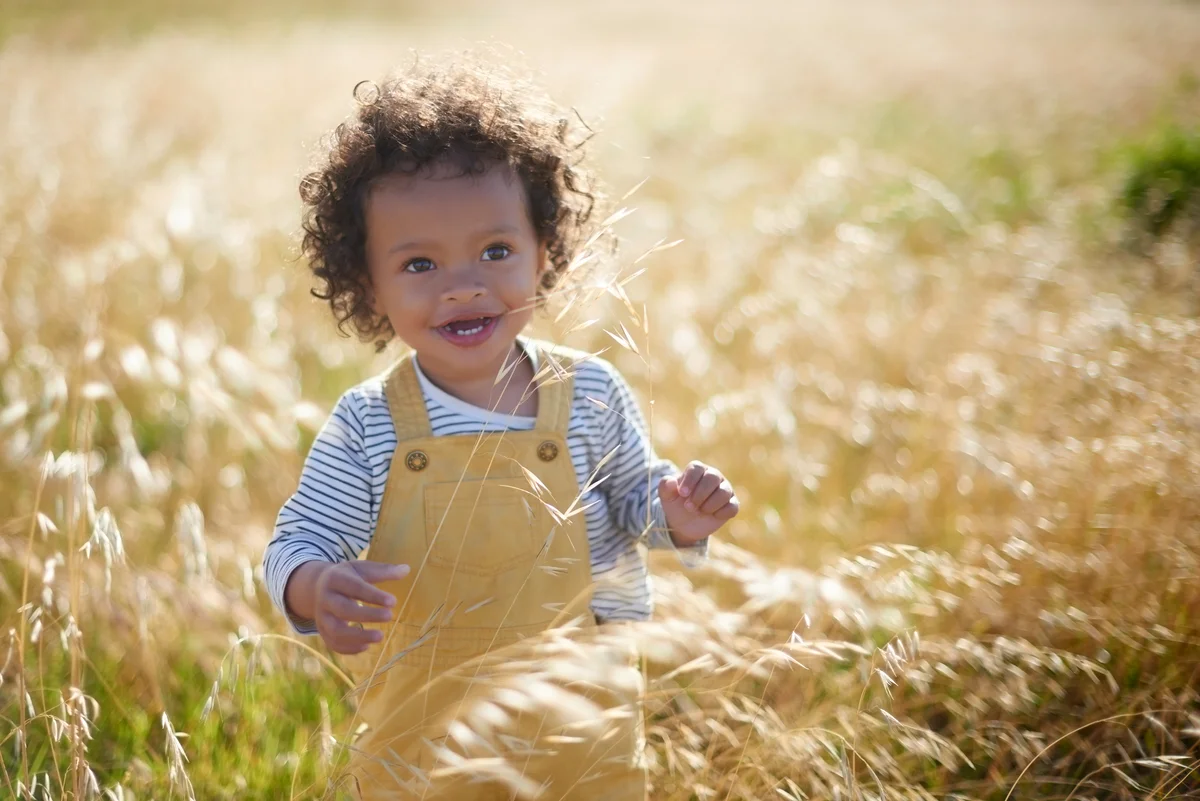 baby and summer with a black girl in a field outdoor