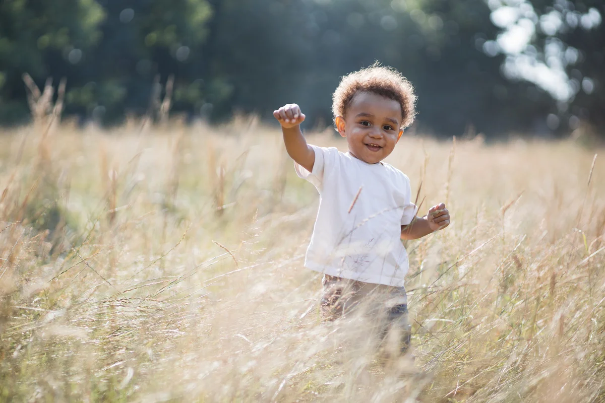Portrait of little african boy standing among high grass